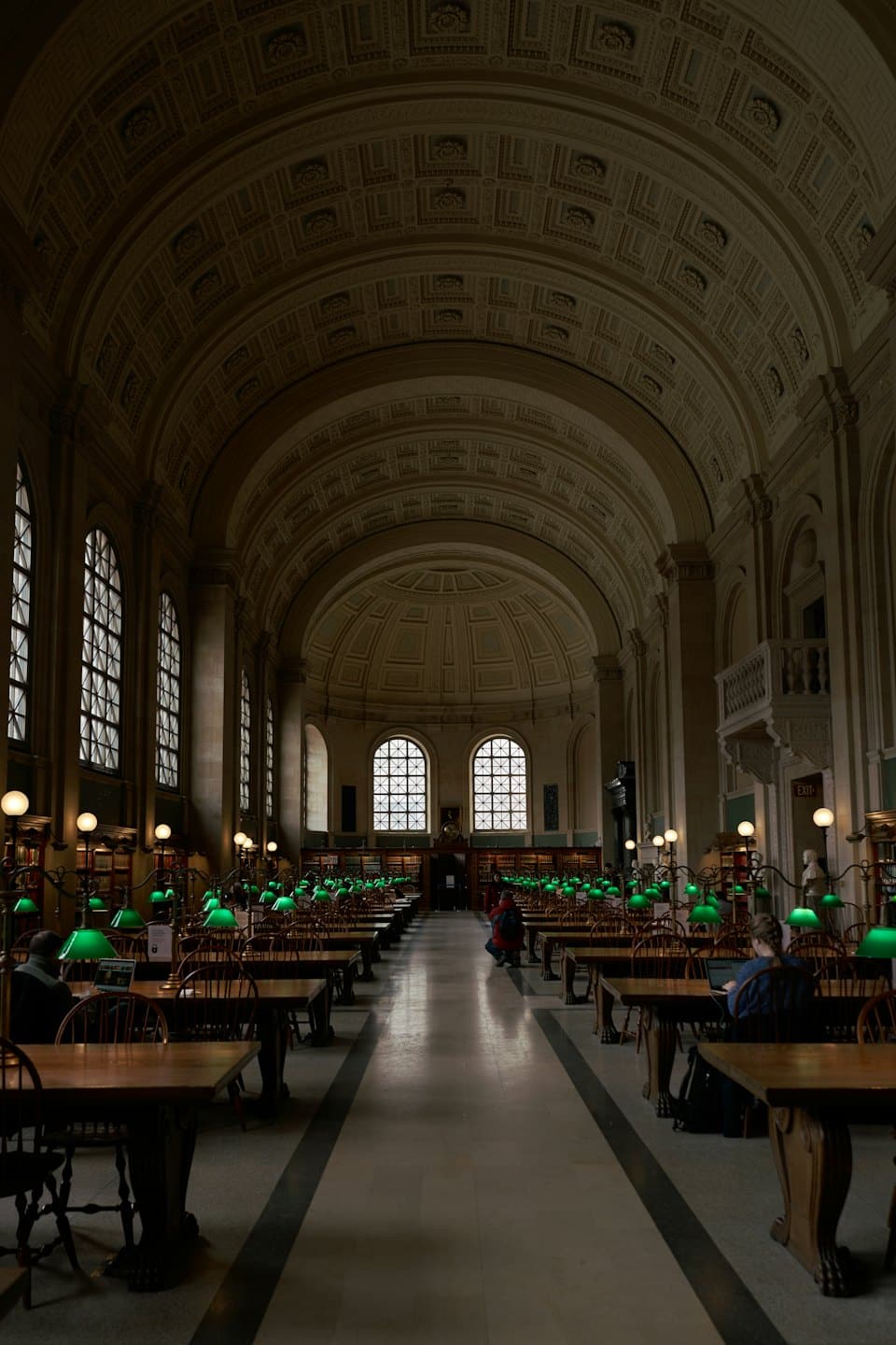 Menschen studieren in einem großen Lesesaal einer Bibliothek mit Gewölbedecken.