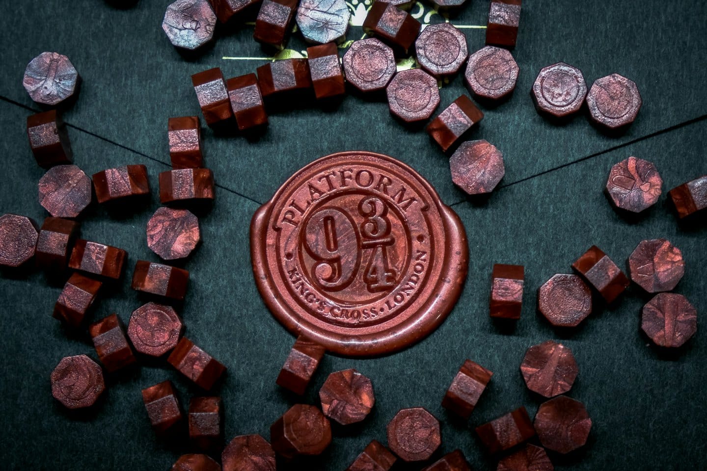 Rötlich-brauner Wachssiegelring, umgeben von passenden Wachspellets.