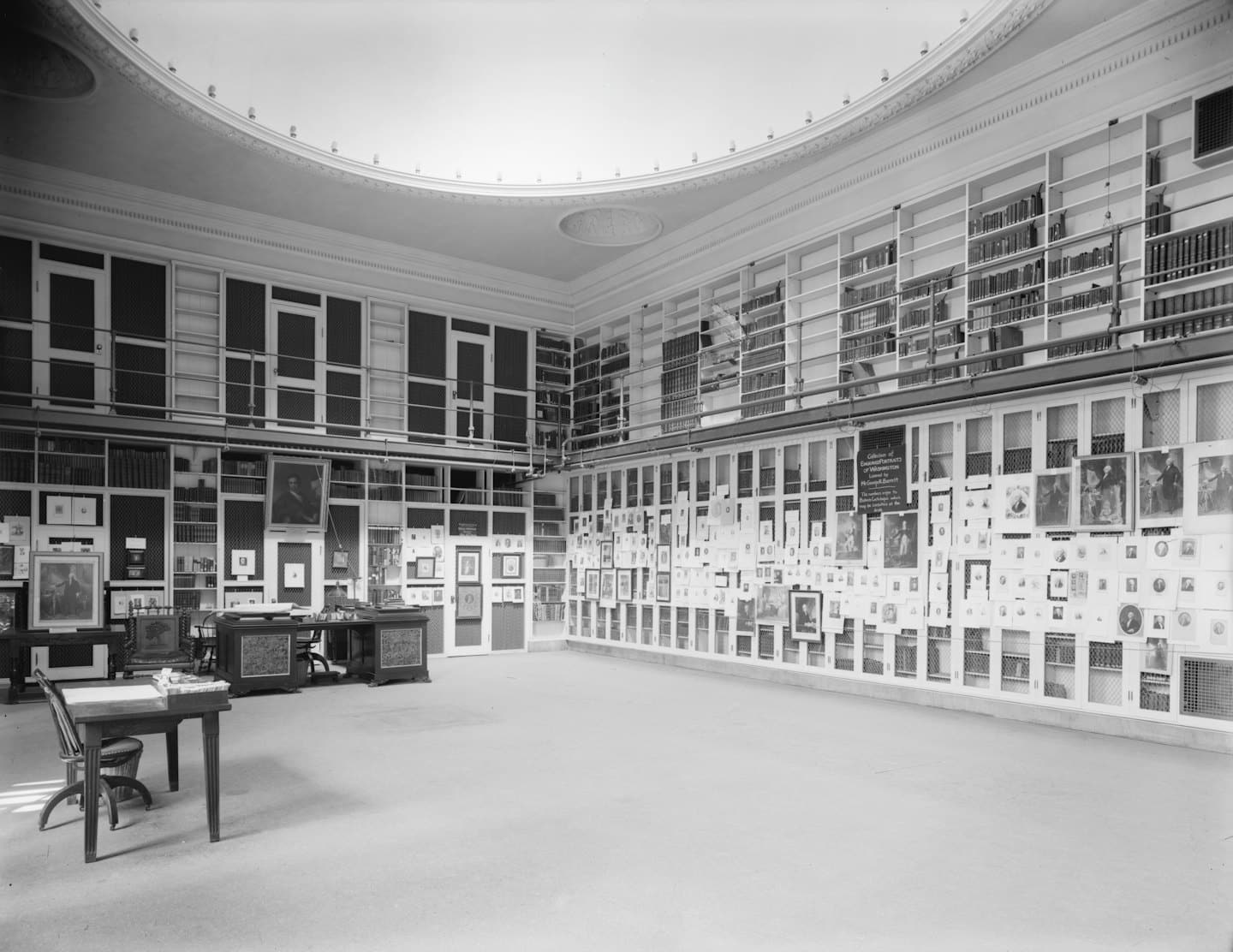 Prunkvolle Holzschreibtische stehen in einer historischen Bibliothek mit hohen Bücherregalen.
