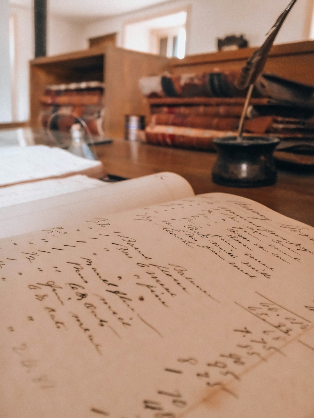 Antiker Kassenbuch mit Schreibfeder und Tintenfass auf einem Schreibtisch.